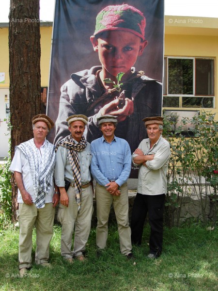 Reza, in checked scarf, second from the left standing in front of one of his photographs.