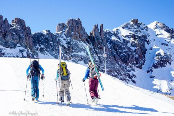 3 women hike to with skiis